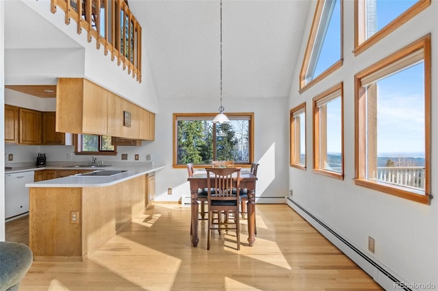 kitchen with dishwasher, a sink, light countertops, a peninsula, and a baseboard heating unit