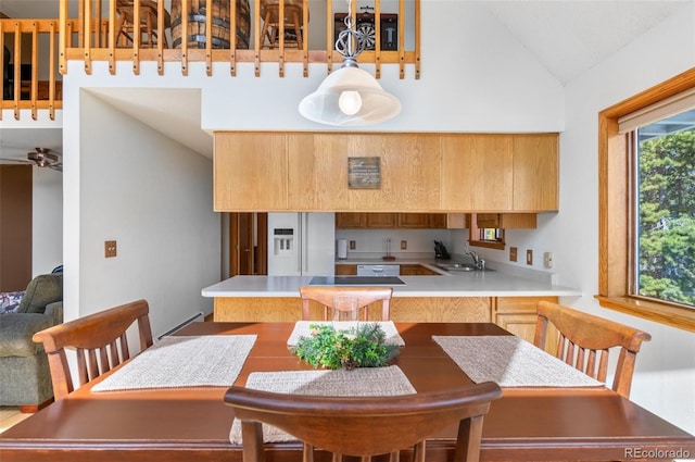 kitchen with a sink, light countertops, a peninsula, and white fridge with ice dispenser