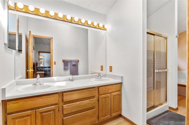 ensuite bathroom featuring a stall shower, double vanity, and a sink