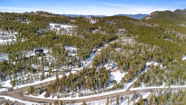snowy aerial view featuring a view of trees and a mountain view