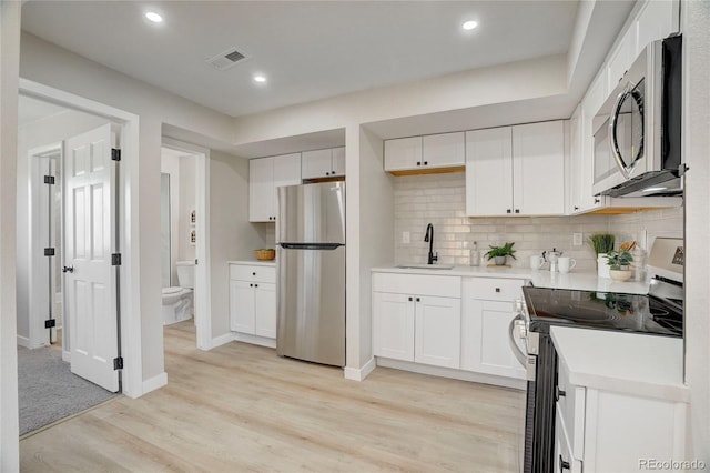 kitchen with visible vents, appliances with stainless steel finishes, light countertops, light wood-style floors, and a sink