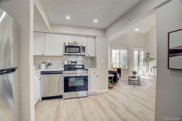 kitchen featuring light wood-style flooring, stainless steel appliances, light countertops, white cabinetry, and backsplash