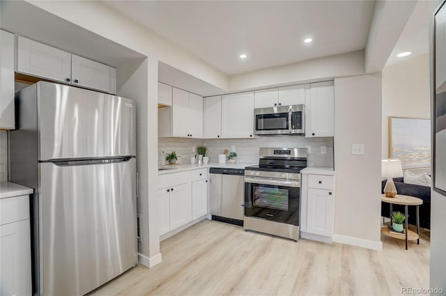 kitchen featuring stainless steel appliances, light wood-type flooring, white cabinets, and light countertops