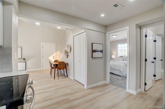 hall with light wood finished floors, baseboards, visible vents, and recessed lighting