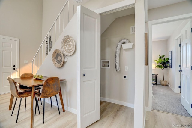 dining area with baseboards, visible vents, light wood finished floors, and stairs