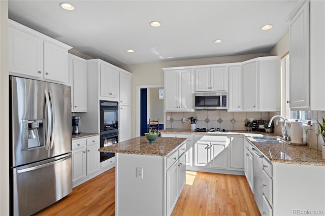 kitchen with black appliances, white cabinetry, light wood finished floors, and a sink