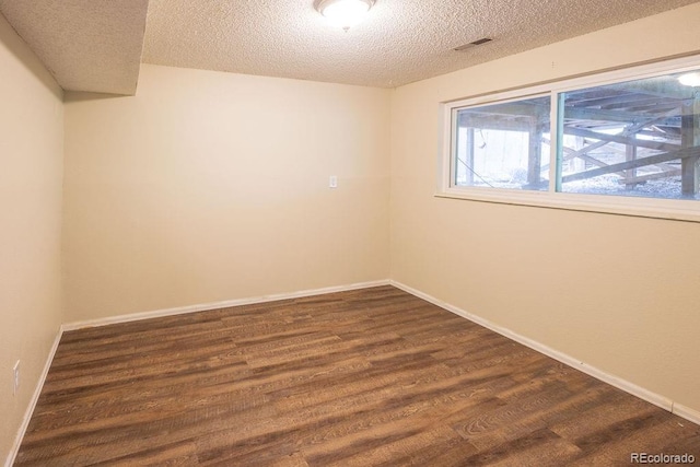 unfurnished room with dark wood-type flooring and a textured ceiling