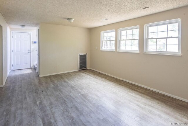 unfurnished room with hardwood / wood-style flooring, plenty of natural light, and a textured ceiling