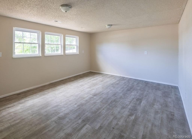 unfurnished room with a textured ceiling and dark hardwood / wood-style flooring