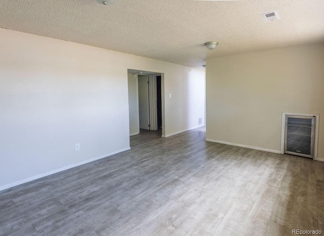 unfurnished room with a textured ceiling and wood-type flooring