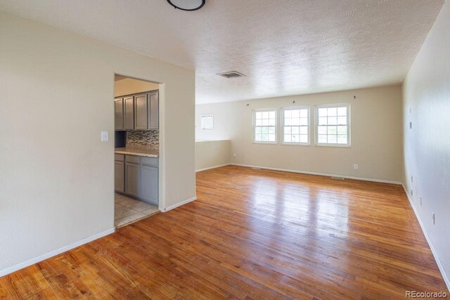 unfurnished room featuring light hardwood / wood-style flooring and a textured ceiling