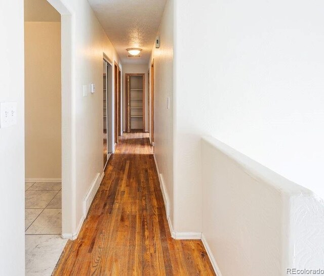 corridor featuring a textured ceiling and hardwood / wood-style floors