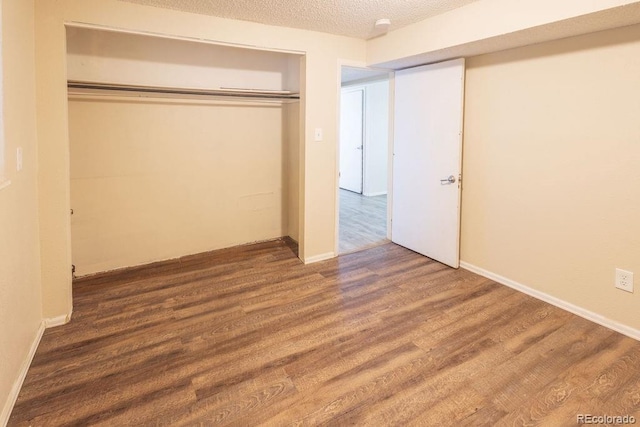 unfurnished bedroom with a textured ceiling, a closet, and dark hardwood / wood-style floors