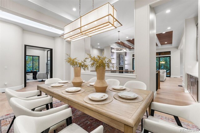 dining area with a notable chandelier, a towering ceiling, and light hardwood / wood-style flooring