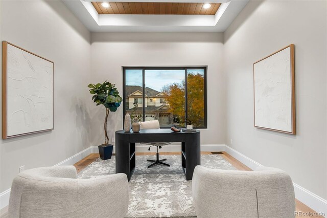 office area with a tray ceiling and hardwood / wood-style flooring