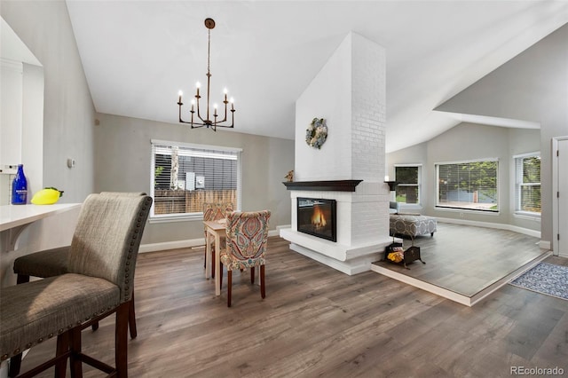 11245 San Joaquin Rdg, Littleton, CO 80127 - dining space with baseboards, high vaulted ceiling, a chandelier, wood finished floors, and a brick fireplace