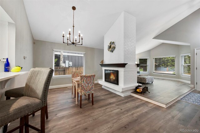 11245 San Joaquin Rdg, Littleton, CO 80127 - dining space with baseboards, high vaulted ceiling, a chandelier, wood finished floors, and a brick fireplace