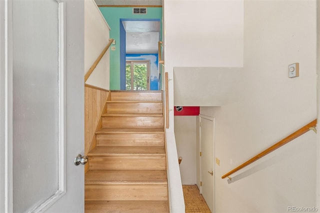 staircase featuring wooden walls