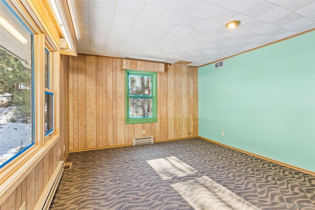 carpeted spare room featuring a baseboard radiator and wood walls