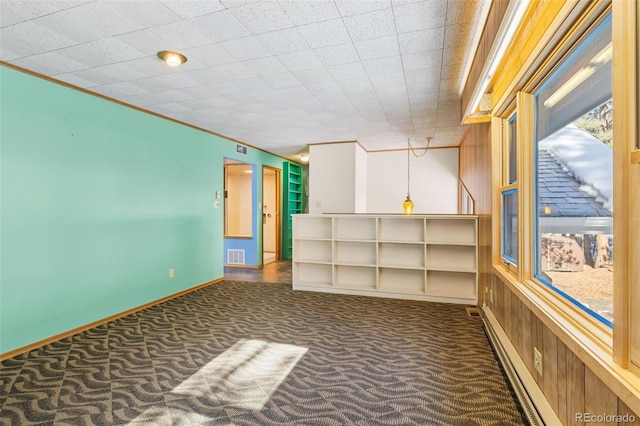 empty room with dark carpet, ornamental molding, and a baseboard radiator