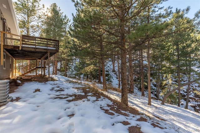 yard layered in snow featuring a wooden deck and central AC unit