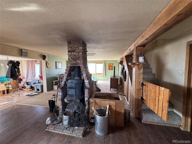 living room featuring dark wood-type flooring, a textured ceiling, and a wood stove