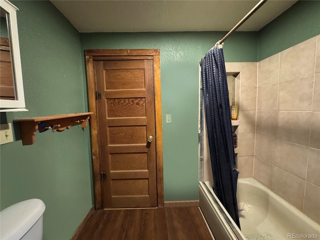 bathroom featuring hardwood / wood-style floors, shower / bathtub combination with curtain, and toilet