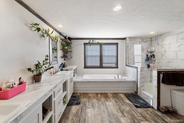 full bath with a garden tub, double vanity, wood finished floors, a sink, and a walk in shower