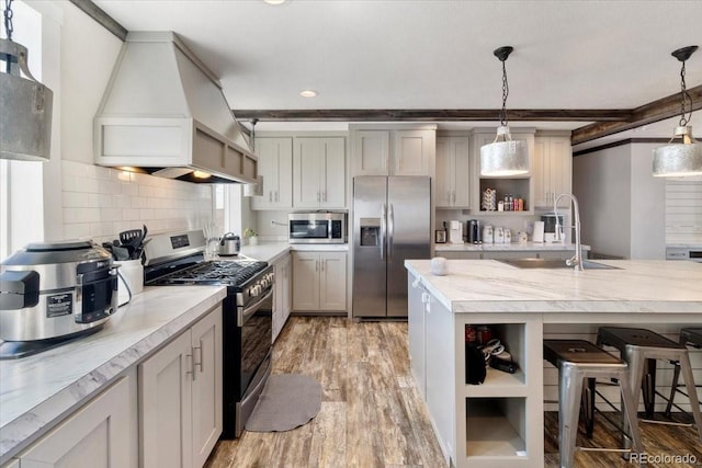 kitchen featuring light wood finished floors, open shelves, appliances with stainless steel finishes, a sink, and premium range hood