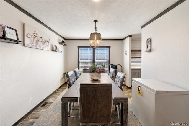 dining room featuring a notable chandelier, visible vents, ornamental molding, a textured ceiling, and baseboards