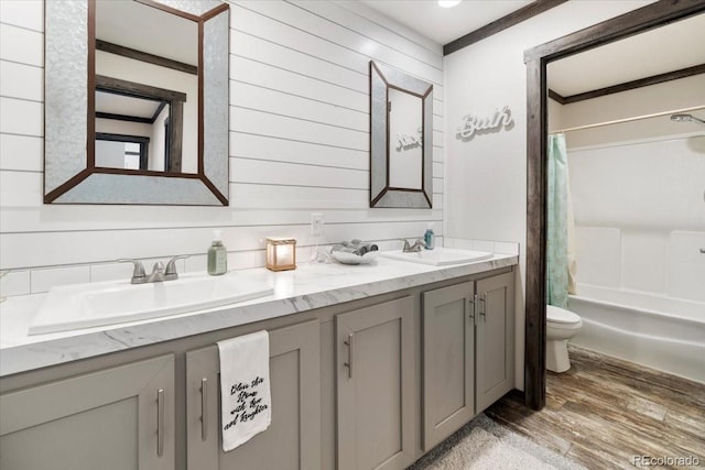 bathroom with wood finished floors, a sink, toilet, and double vanity