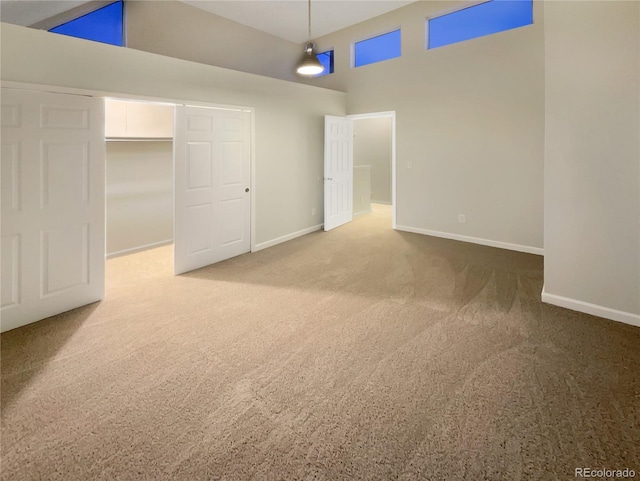 unfurnished bedroom with carpet flooring, high vaulted ceiling, and a closet