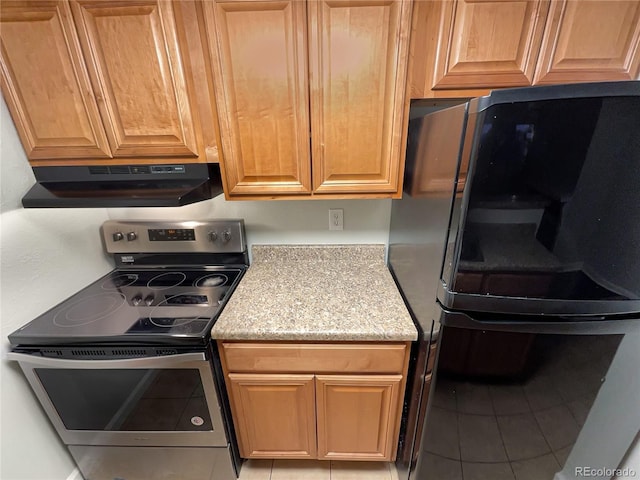 kitchen featuring light stone countertops, black fridge, light tile patterned floors, and stainless steel electric range