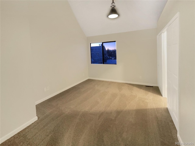 spare room featuring carpet floors and vaulted ceiling