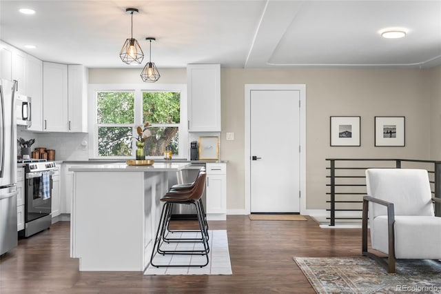 9220 Yucca Way, Thornton, CO 80229 - kitchen with appliances with stainless steel finishes, decorative backsplash, white cabinetry, a center island, and dark wood finished floors