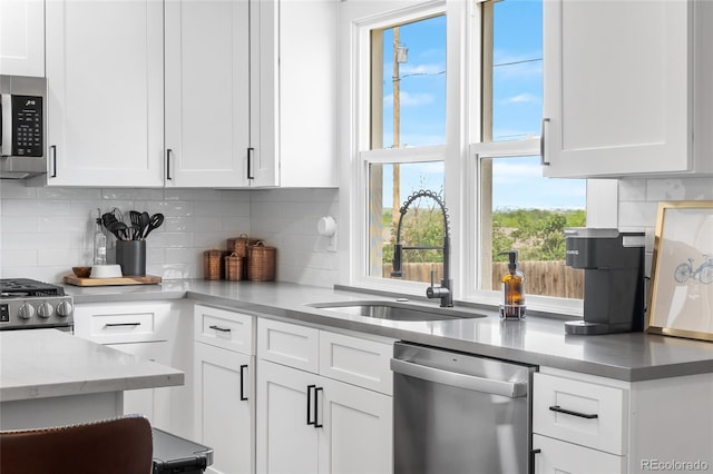 9220 Yucca Way, Thornton, CO 80229 - kitchen featuring appliances with stainless steel finishes, a sink, white cabinetry, and backsplash