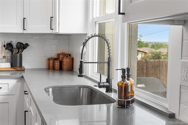 9220 Yucca Way, Thornton, CO 80229 - kitchen view of a sink, white cabinetry, decorative backsplash, and light countertops