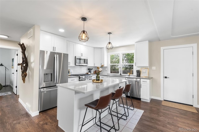 9220 Yucca Way, Thornton, CO 80229 - kitchen with stainless steel appliances, a sink, a breakfast bar, decorative backsplash, and dark wood-style floors