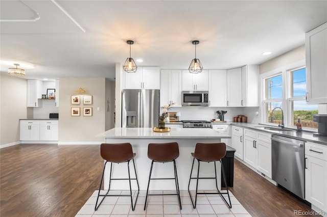 9220 Yucca Way, Thornton, CO 80229 - kitchen with appliances with stainless steel finishes, a sink, a breakfast bar, a kitchen island, and white cabinetry