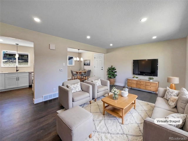 living room featuring a chandelier, wood-type flooring, a textured ceiling, and sink