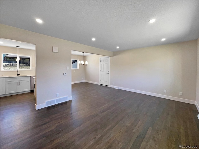 unfurnished living room with a textured ceiling, sink, and dark wood-type flooring