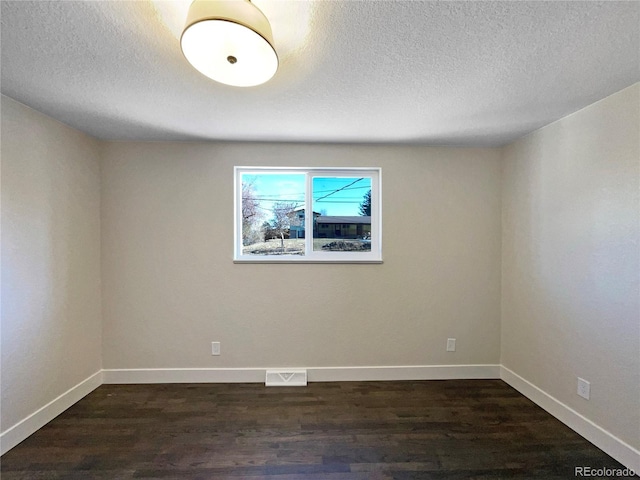 empty room featuring a textured ceiling and dark hardwood / wood-style flooring