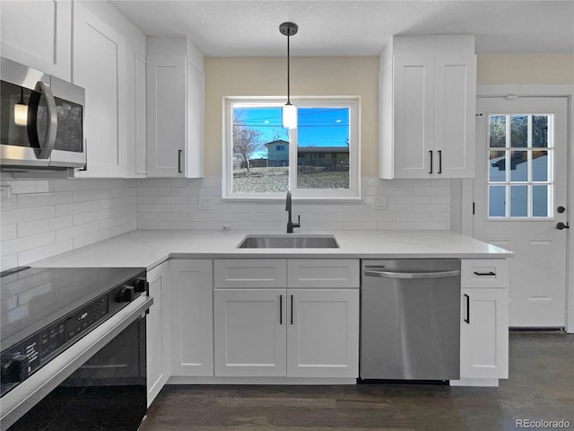 kitchen with stainless steel appliances, sink, decorative light fixtures, dark hardwood / wood-style floors, and white cabinetry