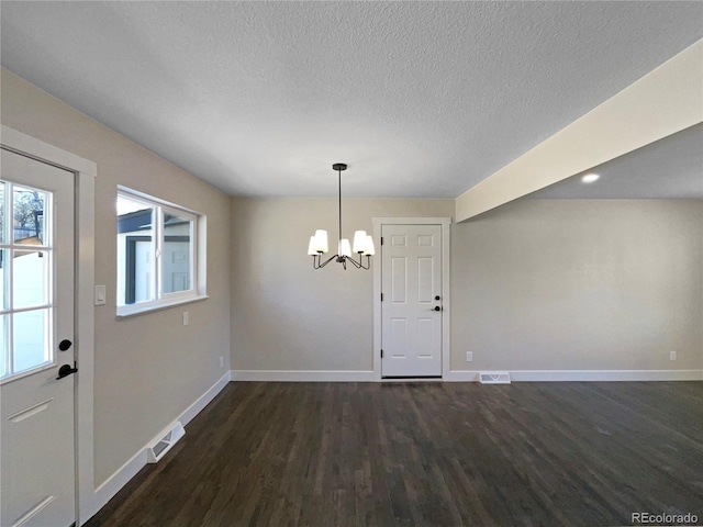 unfurnished dining area with a textured ceiling, a chandelier, and dark hardwood / wood-style floors