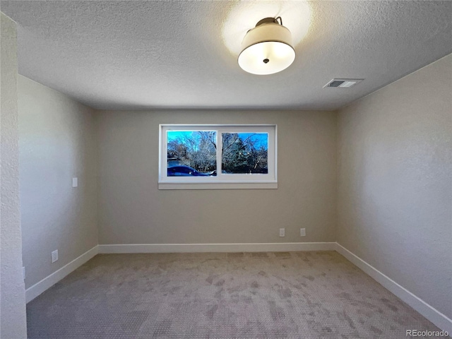 spare room with light colored carpet and a textured ceiling