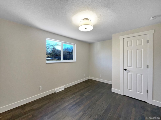 unfurnished room featuring a textured ceiling and dark hardwood / wood-style floors