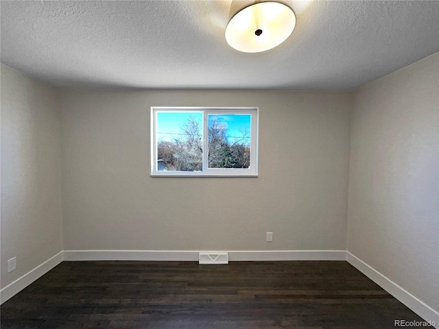 empty room with a textured ceiling and dark hardwood / wood-style flooring