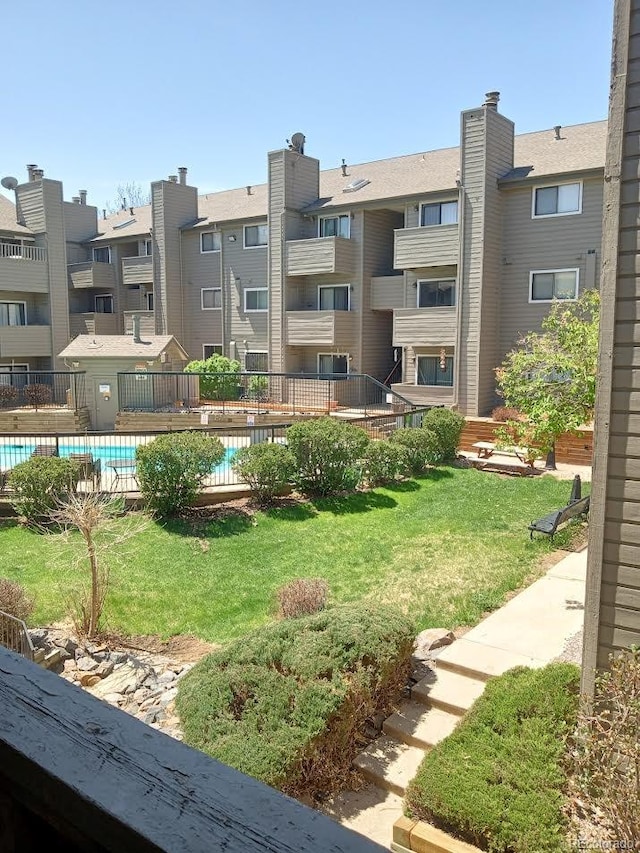 view of home's community featuring a pool and a yard