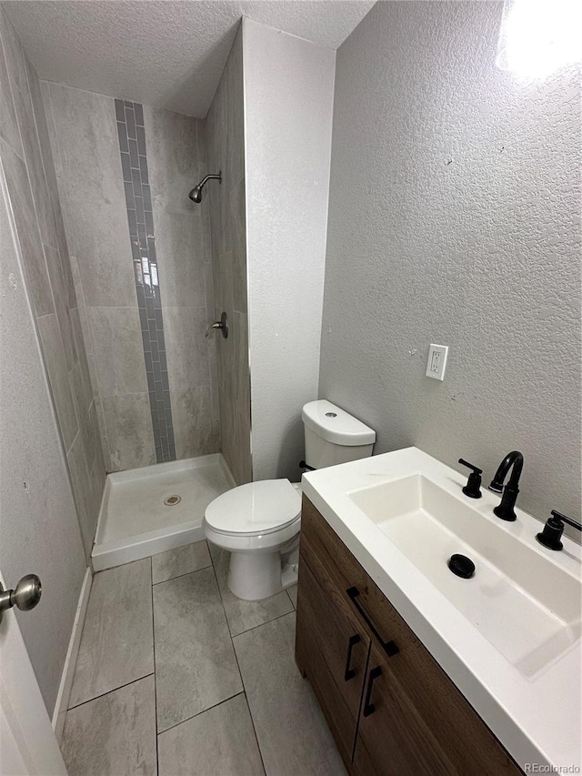 2946 W Park Pl, Denver, CO 80219 - bathroom featuring a tile shower, a textured ceiling, vanity, a textured wall, and tile patterned flooring