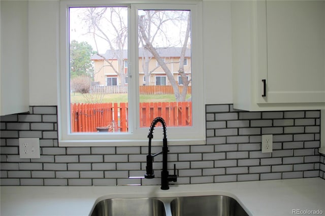 room details featuring white cabinets, decorative backsplash, and sink